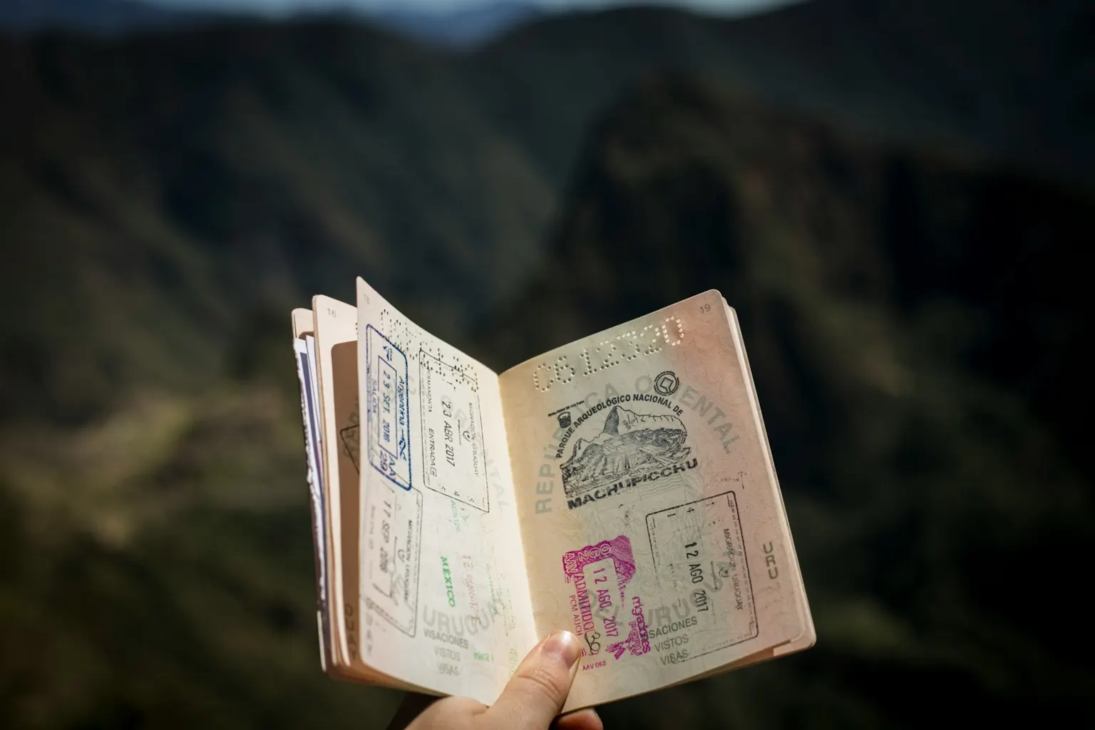 A person holding an open passport with entry stamps